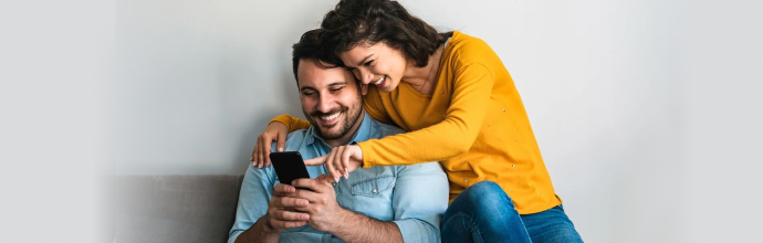 A couple smiling and looking at a smartphone together