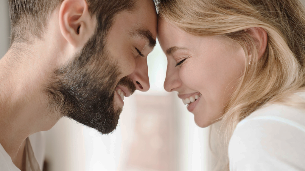 Close-up of a smiling couple with foreheads touching, eyes closed in a moment of affection